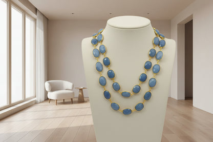 Necklace with blue stones and gold clasps held in a hand against a white background